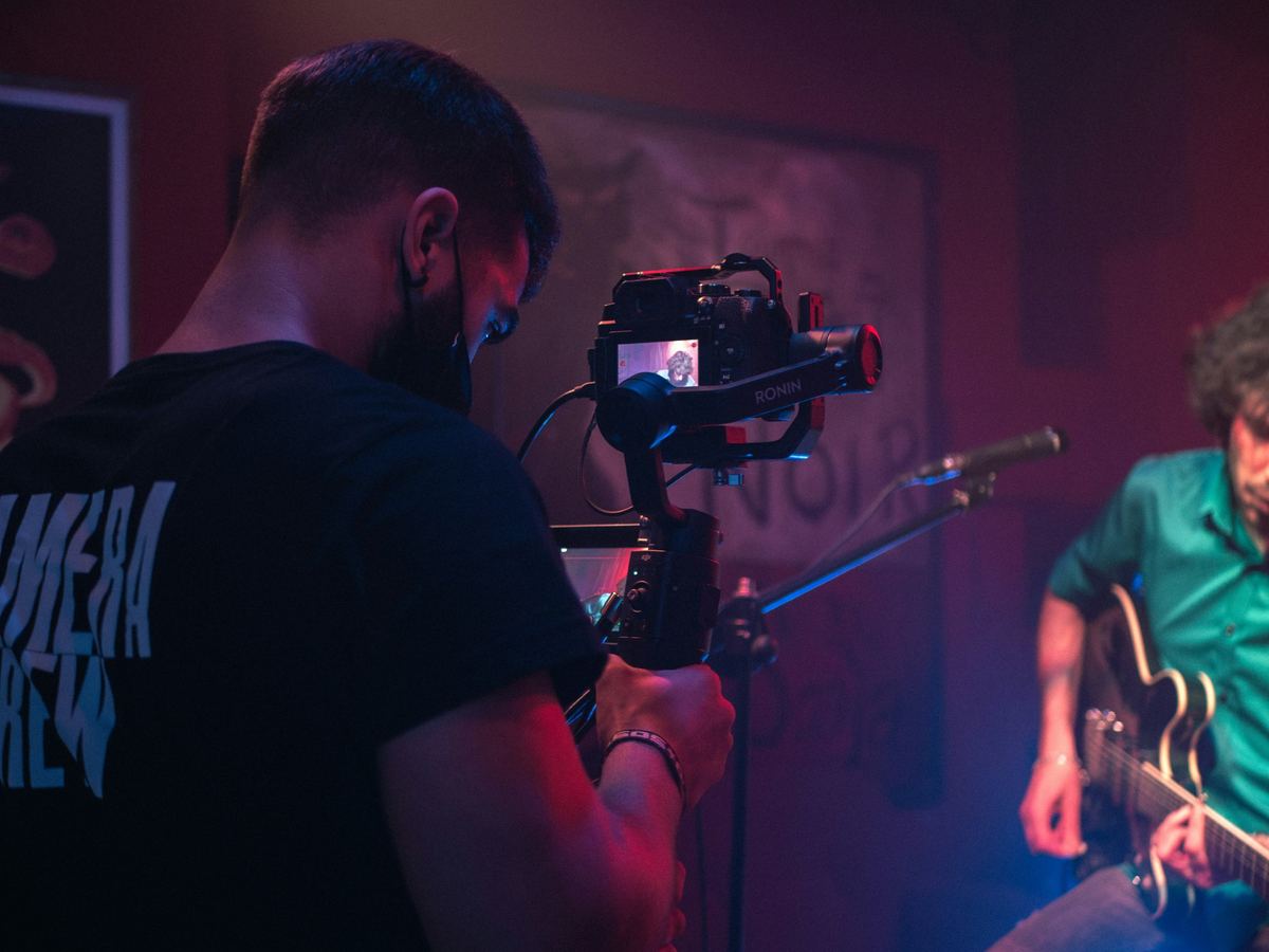 Camera operator filming a guitarist on stage