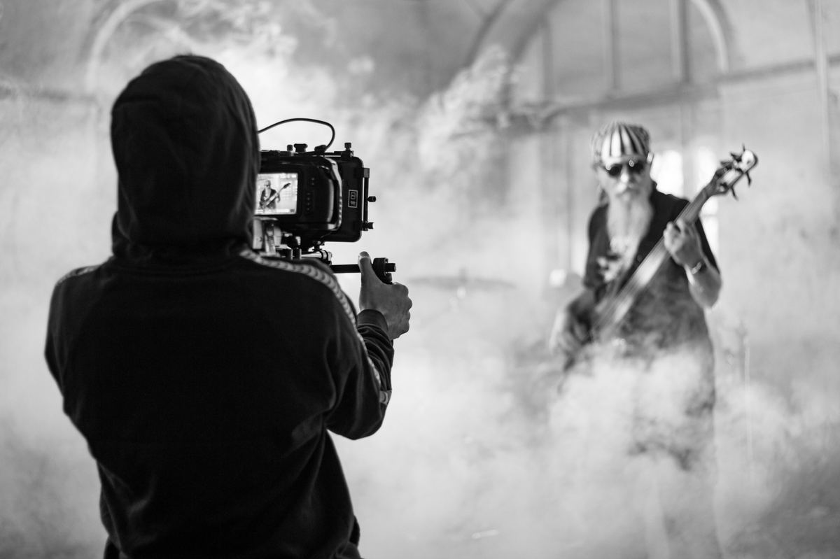 Camera operator filming a bassist through smoke for a concept music video