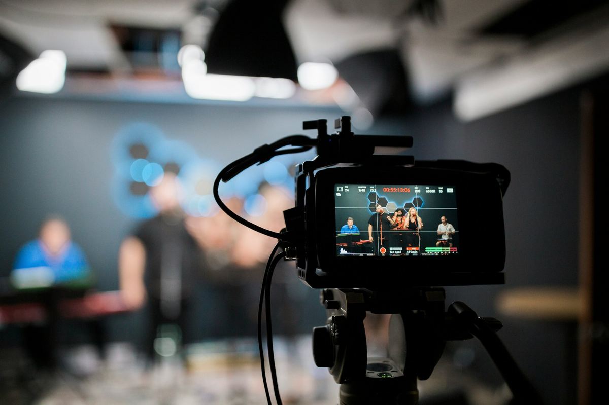 Camera on a tripod showing a live band on its screen