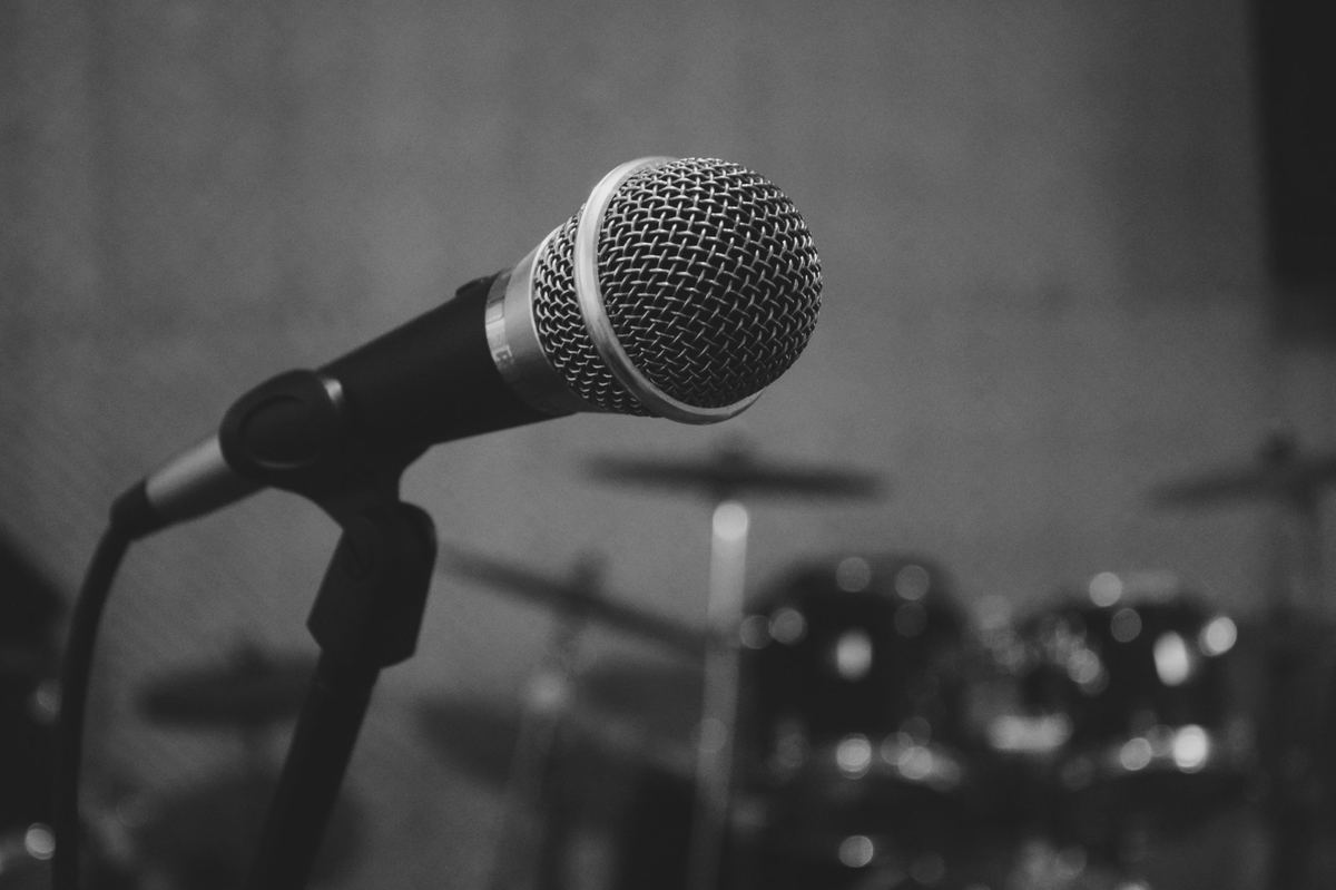 Microphone on a stand in a rehearsal room with a drum kit behind