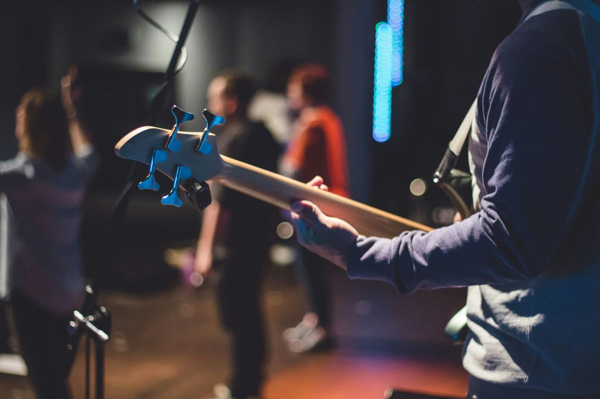 Bass guitar neck with band rehearsing in a blurred studio background